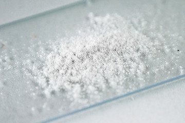 white powder (cocaine, heroin, synthetic drug, medicine) on a medical glass