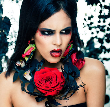 pretty brunette woman with rose jewelry, black and red, bright make up a vampire closeup red lips