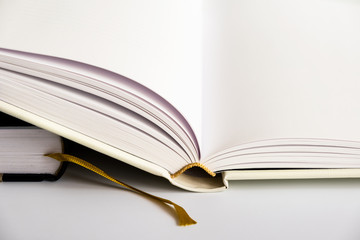 Opened blank hardcover book with ribbon bookmark. Isolated closeup on a white background. Copy space..