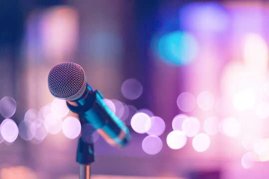 Close up of high fidelity microphone setting on stand with colorful abstract light bokeh background in conference seminar hall . Microphone on stage banner size.