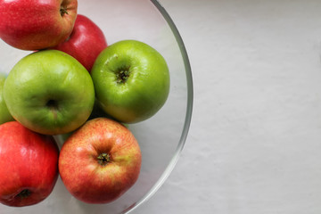 red and green apples in a bowl  on a white background, copy space