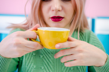 Beautiful young girl with red lipstick drinking tea in cafe. Clouse up photo