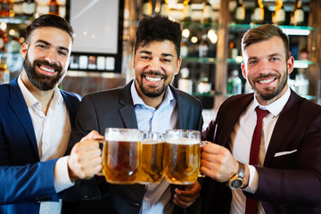 Group of happy friends drinking beer at the pub and having fun