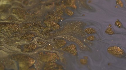 Gold liquid glitter paint texture. Abstract background. Macro. Motion mixed colorful ink