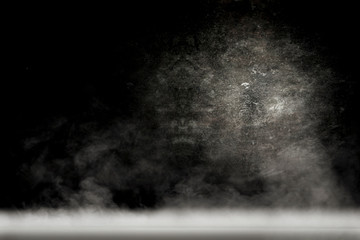 Desk of free space and black background with smoke decoration. 