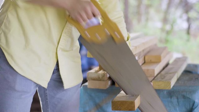 Man Sawing Wood Outside with a Handsaw