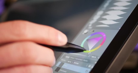 A freelance digital artist or designer selecting a color hue and painting with a drawing graphic tablet and pen in an art studio. - Powered by Adobe