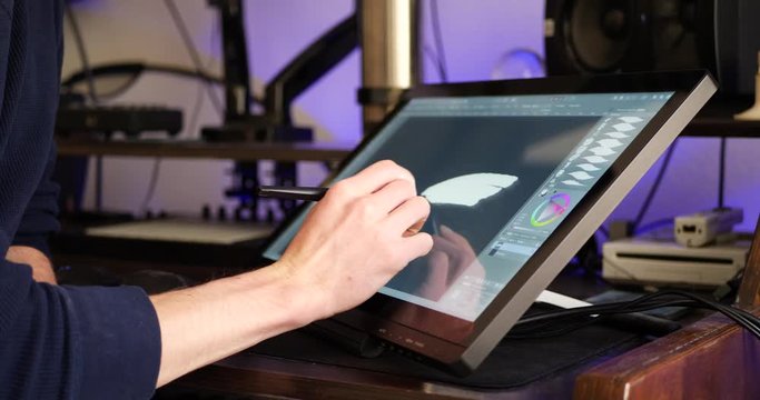 A freelance digital artist or designer sketching and painting in brushstroke with a drawing graphic tablet and pen in an art studio.