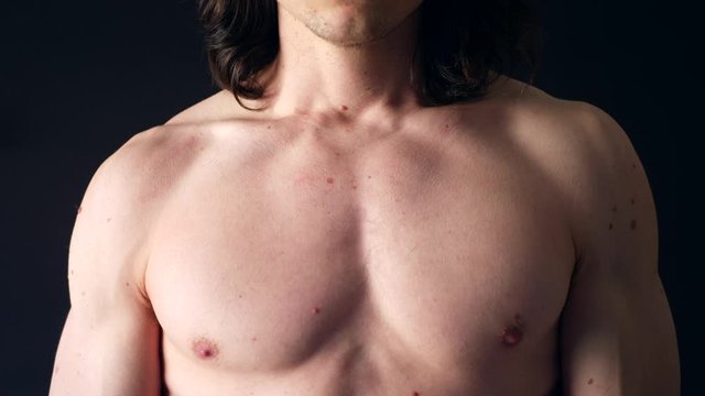 A strong shirtless white man flexing his upper body chest muscles in the gym after a tough fitness training workout.