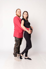 Fototapeta premium Caucasian man with a beard in a red sweater hugs a pregnant Caucasian girl