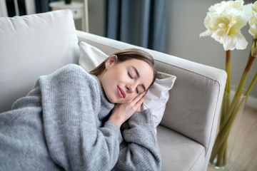 Young girl in a grey sweater sleeping on a sofa