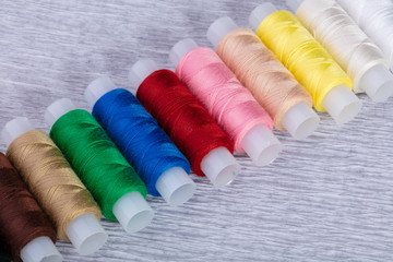 Multi-colored spools of thread on a gray background.