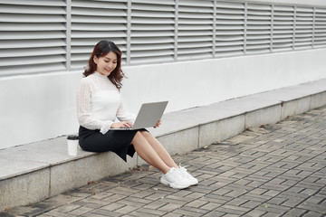 Happy hipster young woman working on laptop in the park