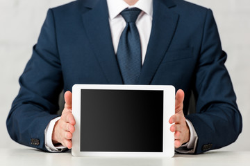 cropped view of businessman in suit holding digital tablet with blank screen on white