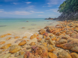view of many rocks on sand beach with blue-green sea and blue sky background, Kwang Peeb Beach (Ao Kwang Peeb), Ko Phayam island, Ranong, Thailand.