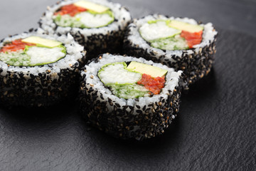 Sushi Rolls with vegetables on a dark background. Sushi set on a stone plate and dark concrete background. Sushi roll set and chopsticks. Fresh Japanese cuisine. asian food. Sushi image for menu. clos