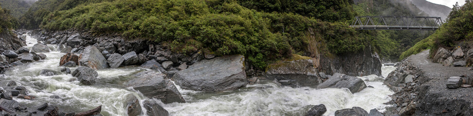 Naklejka na ściany i meble Panorama. Stream. Creek. Rocks. Fast streaming water. Mount Aspiring National Park. Haast highway 6. Westcoast New Zealand.