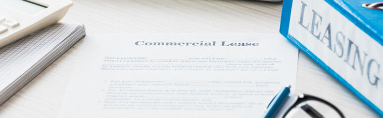 panoramic shot of folder near document with commercial lease lettering on desk