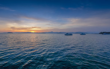 view panorama morning of the boats floating in the sea with red sun light and blue sky background, sunrise at front beach, Ko Phayam (ko payam) island, Ranong, southern of Thailand.