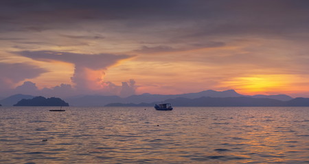 Sea view panorama morning of fishing boat running in the sea with purple sky background, sunrise at front beach, Ko Phayam island, Ranong Province, southern of Thailand.