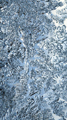 Ice crystals very close up on a window pane in winter. Frozen water. Mystical fabulous abstract pattern. Weather forecast: frost, cooling. Blue background or wallpaper. Strong macro plan