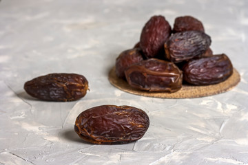 Tasty royal dates on a round plate close-up on a concrete white-gray background