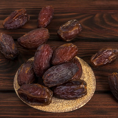 Tasty royal dates on a round substrate close-up on a wooden background