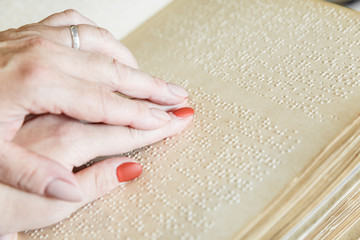 woman reading braille text on old book