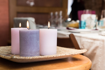 Group of three burning candles in the home. Candles of pink tones in a warm house.