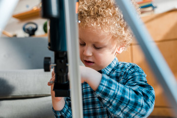 selective focus of curly kid looking at telescope
