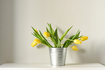 Beautiful spring yellow tulips in an abstract vase on the shelf, interior, sunny room - Powered by Adobe