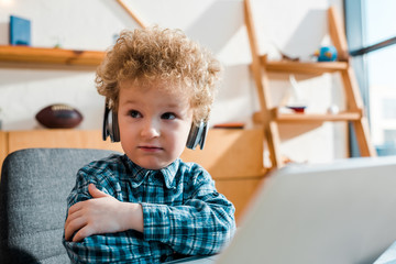selective focus of kid listening music in wireless headphones near laptop