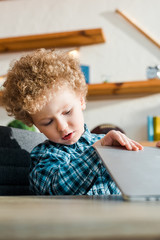 selective focus of smart and curly kid using laptop