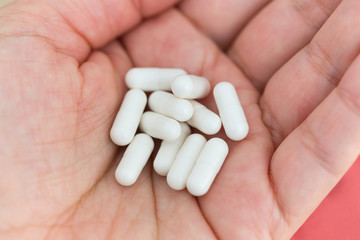 A handful of white medical capsules of medicine in the palm of hand. Medical background