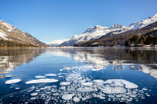 Trapped methane bubbles under the frozen lake with landscape as background