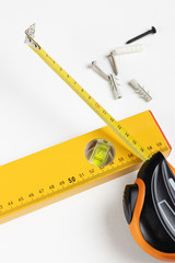 Yellow tape measure spirit level and scaffolding dowels and self-tapping screws on clear white background. Place for text.