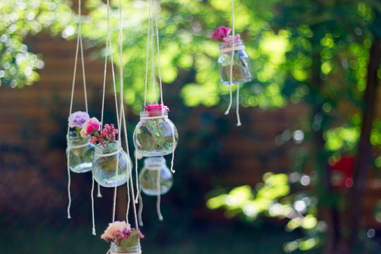 Decoration glass jar with flowers hanging with blur garden background. Soft focus