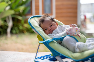 newborn infant on baby bouncer at home
