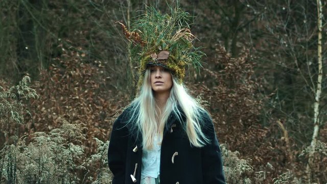 Beautiful Wiccan woman in nature crown walks in winter flurry