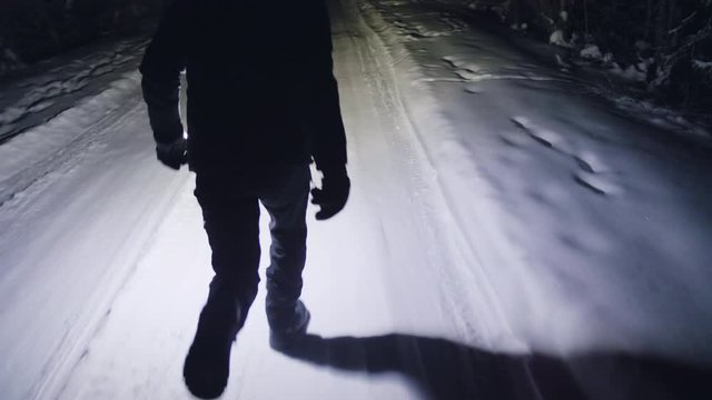Slow motion of person running at dark night with flashlight on snow