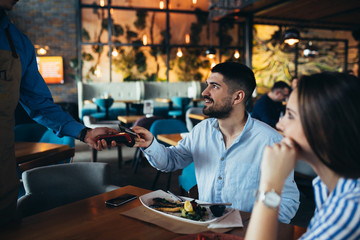 man paying with credit or debit card in restaurant