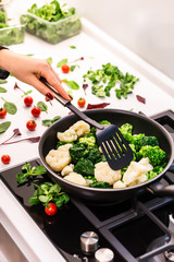  Cooking healthy organic food. Organic tomatoes, spinach, arugula, cauliflower and fresh green meat. Vegetarian food.  Vegetables in a pan.