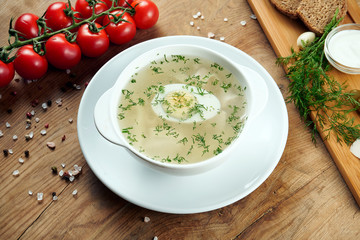 Dietary soup with chicken, vegetables and parsley in compostion with ingridients on wooden background in white bowl. Top view tasty soup. Flat lay food
