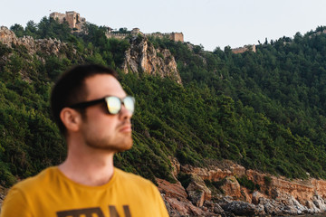 Beautiful views of the cliffs and castle of Alanya, Turkey and a cute man in sunglasses in the...