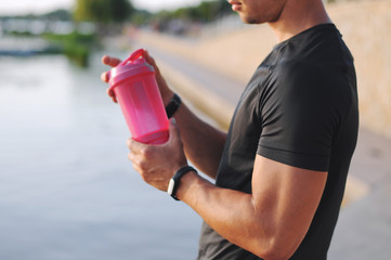 Man with fitness tracker holding a shaker.	
