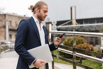 Handsome young bearded businessman standing outdoors