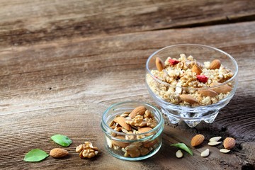 Breakfast cereals in a bowl.  Fresh granola, muesli  with almonds and walnuts on wooden table. Basil leaves. Copy space