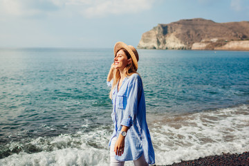 Traveler woman walking along shore of Red beach on Santorini island, Greece. Traveling and vacation...