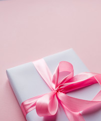 Festive pink bow on a white box. Place for text. Clouse up