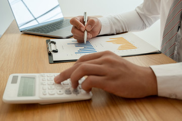 A business man is sitting at a desk and calculating financial graphs about real estate investment expenditures